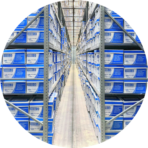 Photo looking down a long warehouse aisle at tall metal shelving holding organized stacks of identical blue and white boxes